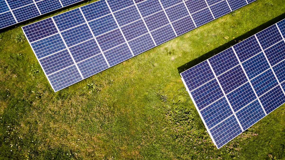 Aerial view of a solar farm of photovoltaic panels above green meadows