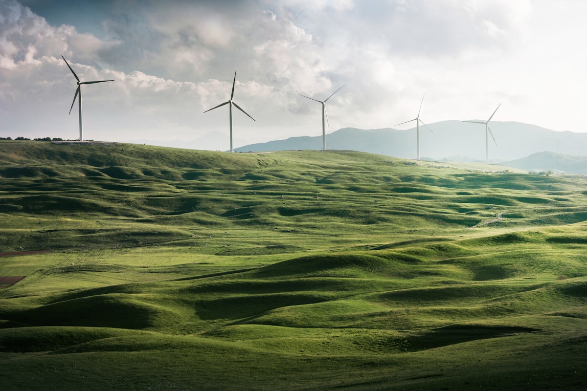 White wind turbines next to a green field under soft skies on the inland Spanish plateau